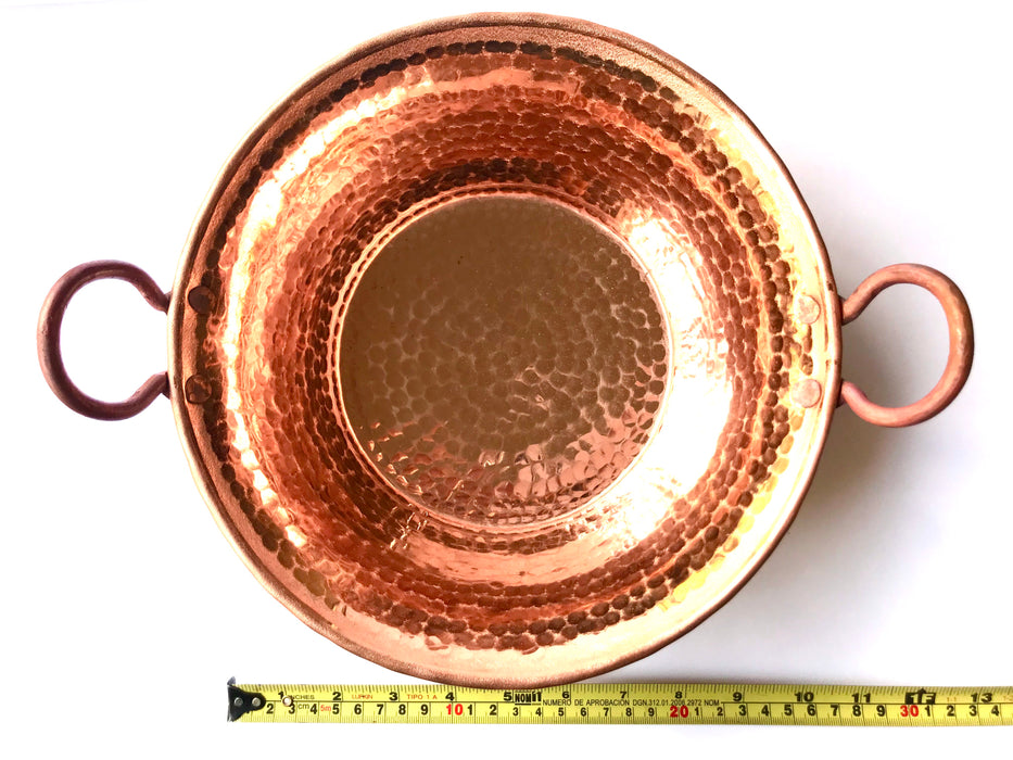 Mexico 1492: A hammered copper saucepan (or better known as cazo in Mexico), handmade in Santa Clara del Cobre, by one of the oldest, most respected coppersmith workshops of don Viduel. The copper hammering process is lengthy and arduous, but the shaping is done through a series of soft hammer blows that create the recognizable indentations on the surface. 