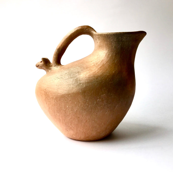 Mexico 1492: Stunning pitcher with an animal head ornament, made from red clay with a yellowish and gray tone and marked with random flame spots, adding character. Best for serving water, refreshing drinks, or even as a vase. Lead free, unglazed. Thanks to the artisanal nature of this handmade product, no two pieces are the same. 