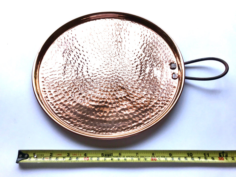 Mexico 1492: A shiny copper comal, hammered by hand. Comal (from the Nahuatl comalli) is a flat surface that, placed over fire or a stove burner, served through centuries to cook tortillas, tlacoyos, gorditas, or roast cocoa beans, and in recent centuries, coffee. 